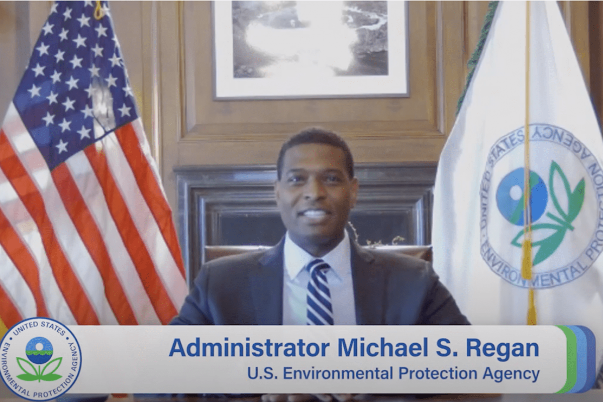 US EPA Administrator Michael S. Regan sitting at a desk with an American flag and EPA flag behind him.
