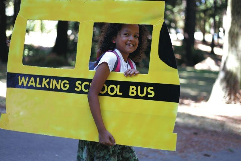 Girl holding a cardboard with school bus illustrated