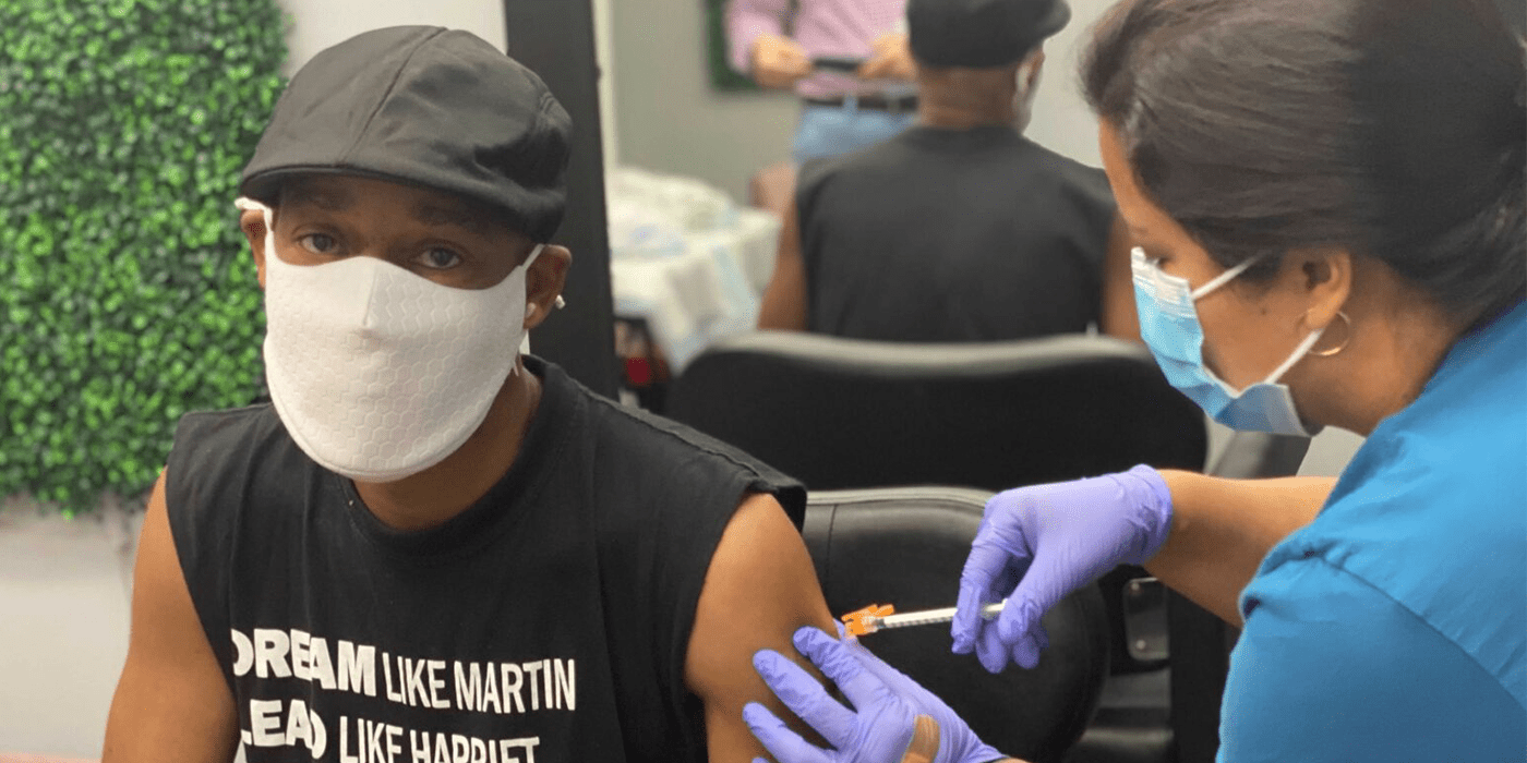 Black man receiving COVID vaccine in local barber shop