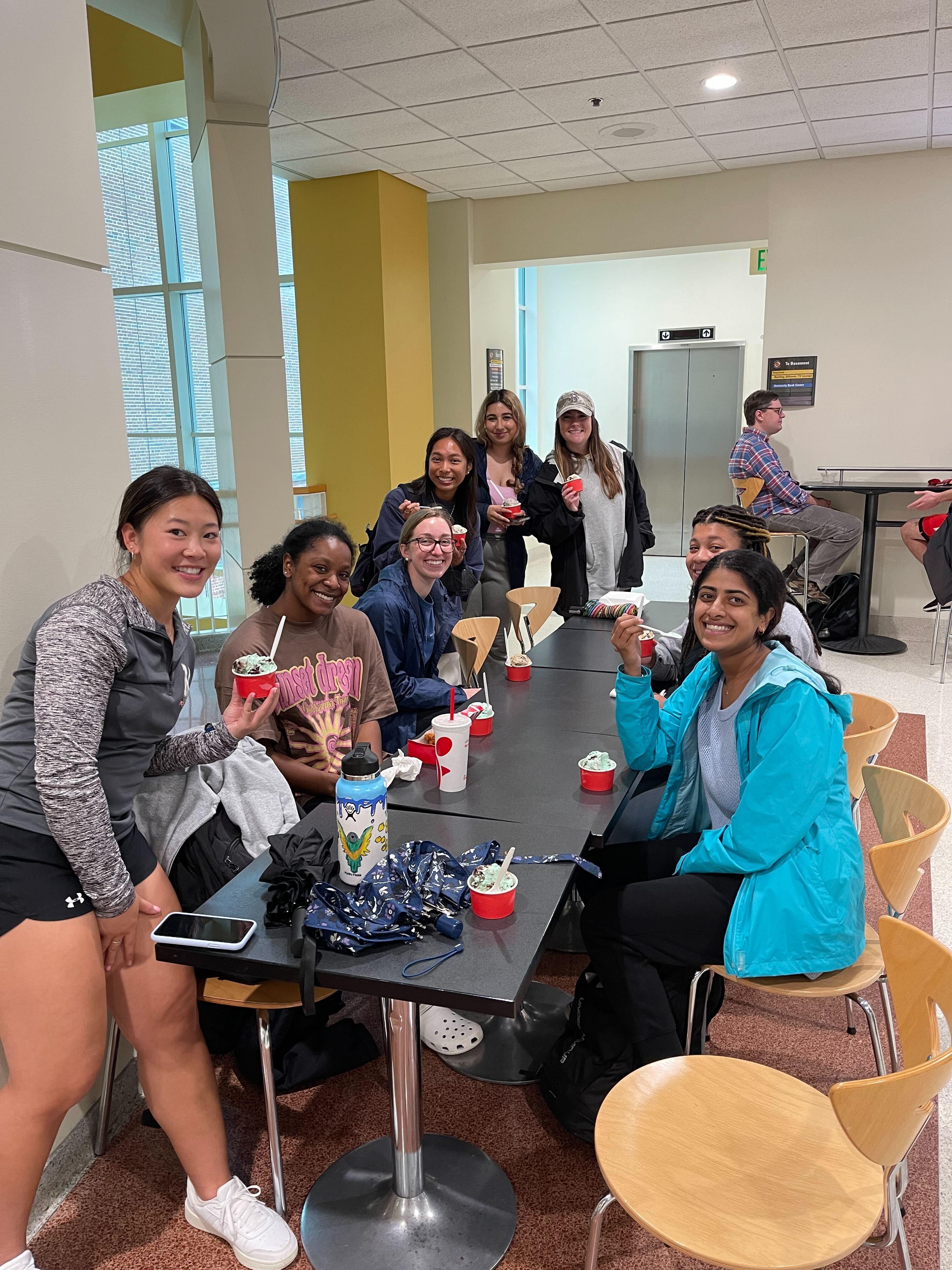 Students sit at table eating ice cream